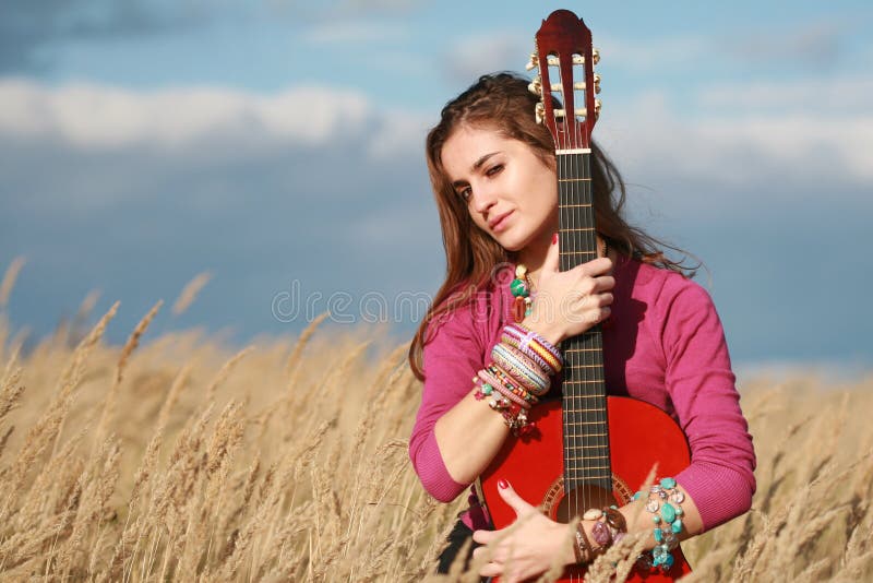 Fille retenant une guitare dans le domaine images stock Fille retenant une guitare dans le domaine images stock