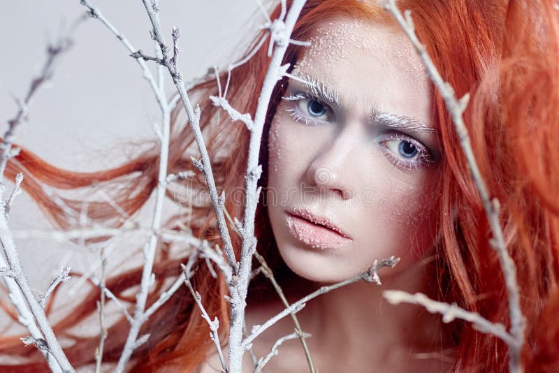 Fille rousse avec de longs cheveux, un visage couvert de neige avec les sourcils blancs de gel et des cils dans le gel, une branc photographie stock Fille rousse avec de longs cheveux, un visage couvert de neige avec les sourcils blancs de gel et des cils dans le gel, une branc photographie stock
