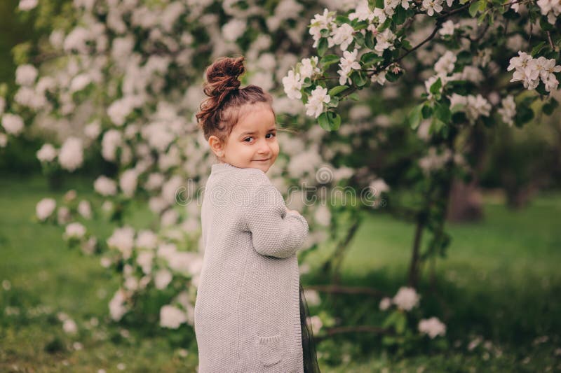 Fille rêveuse heureuse mignonne d'enfant d'enfant en bas âge marchant dans le jardin de floraison de ressort, célébrant Pâques ex photo stock Fille rêveuse heureuse mignonne d'enfant d'enfant en bas âge marchant dans le jardin de floraison de ressort, célébrant Pâques ex photo stock