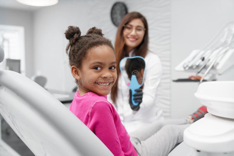 Fille s'asseyant sur la chaise de dentiste regardant la caméra et le sourire images libres de droits Fille s'asseyant sur la chaise de dentiste regardant la caméra et le sourire images libres de droits