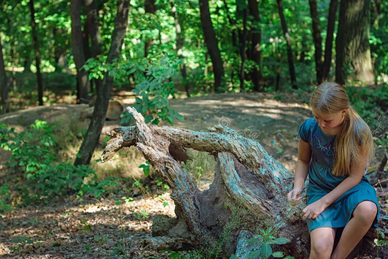 Fille s'asseyant sur un tronçon d'arbre images libres de droits Fille s'asseyant sur un tronçon d'arbre images libres de droits