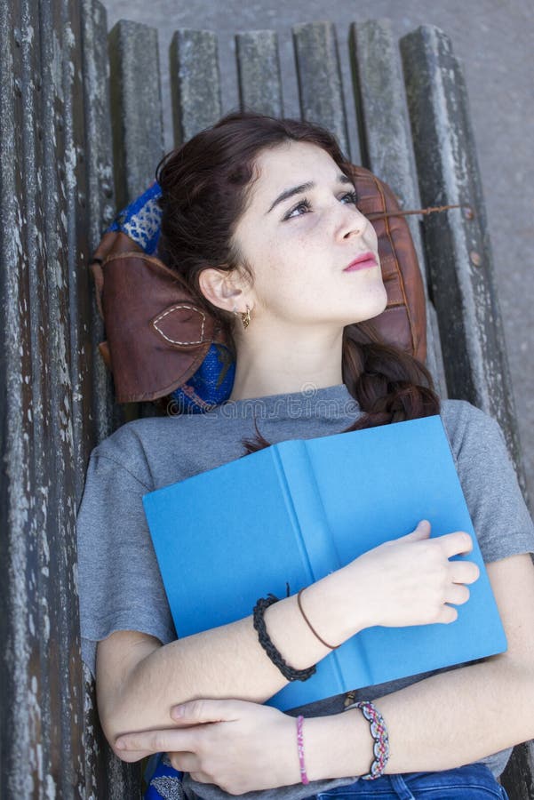 Fille songeuse de hippie se trouvant sur le banc avec le livre bleu, lifestyl d'adolescence photo libre de droits