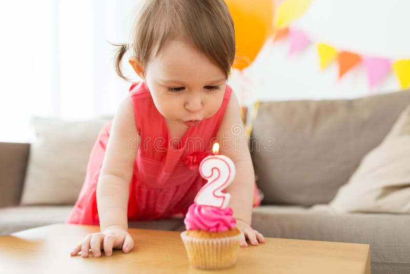 Fille soufflant à la bougie sur le petit gâteau à l'anniversaire photo libre de droits Fille soufflant à la bougie sur le petit gâteau à l'anniversaire photo libre de droits