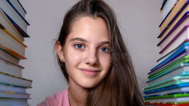 Fille souriante entourée de livres colorés. closeup d'une fille souriante encadrée de piles de livres colorés symbolisant images stock