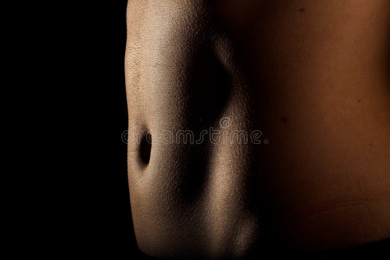 Belly and abs of a sport woman in low key on a black background. Belly and abs of a sport woman in low key on a black background