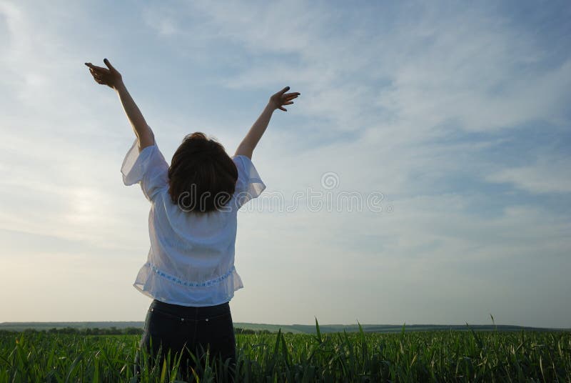 The girl on a field. The woman with the lifted hands to the sky on a green meadow. The girl on a field. The woman with the lifted hands to the sky on a green meadow