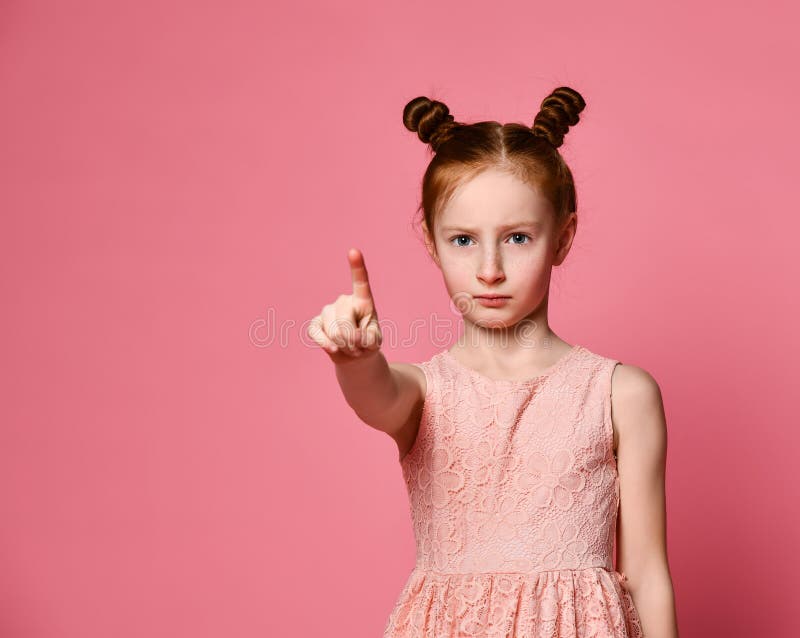 Fille sérieuse rousse au-dessus du mur rose se dirigeant avec confiance à vous avec un doigt photographie stock Fille sérieuse rousse au-dessus du mur rose se dirigeant avec confiance à vous avec un doigt photographie stock