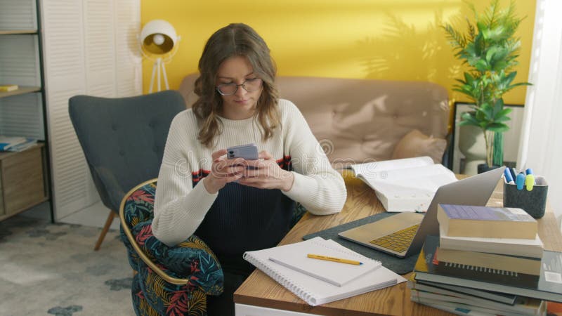 Fille taper le message sur le smartphone à la maison. étudiant se reposer entre les leçons banque de vidéos