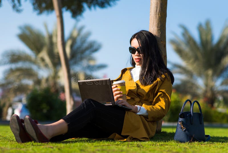 Fille travaillant sur l'ordinateur portable en parc image stock Fille travaillant sur l'ordinateur portable en parc image stock