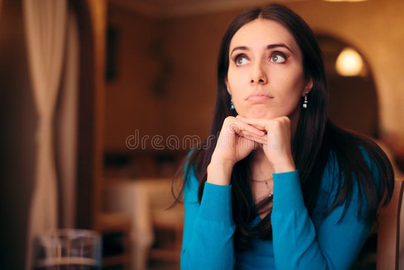 Fille triste attendant sa date dans un restaurant images libres de droits Fille triste attendant sa date dans un restaurant images libres de droits