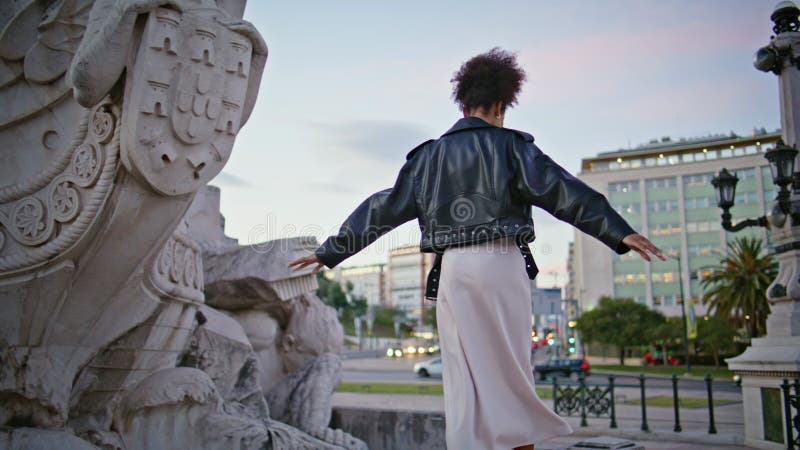 Fille à la découverte de l'architecture historique au crépuscule venteux. femme africaine marchant banque de vidéos
