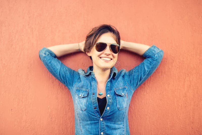 Fille à la mode de brune, faisant des expressions de visage, souriant et riant sur le fond orange, d'isolement Style de vie moder image stock Fille à la mode de brune, faisant des expressions de visage, souriant et riant sur le fond orange, d'isolement Style de vie moder image stock