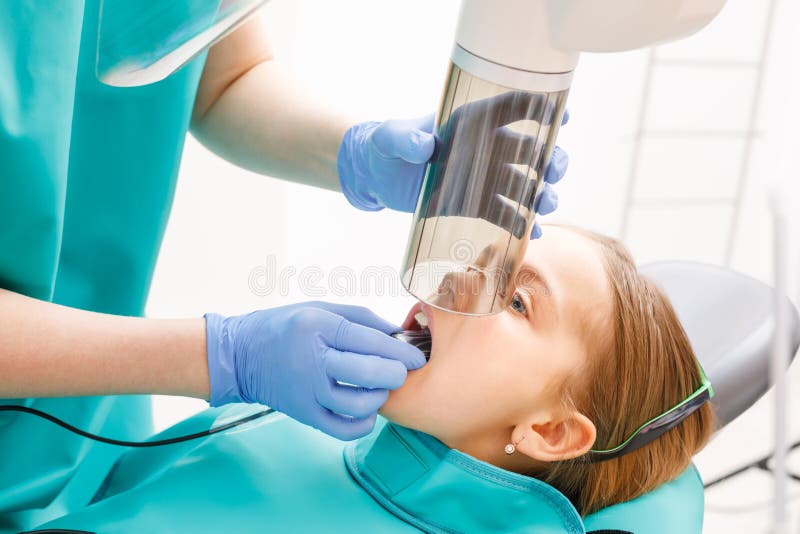 Fille élémentaire d'âge recevant la radiographie ou le rayon X dentaire dans la clinique dentaire pédiatrique image stock Fille élémentaire d'âge recevant la radiographie ou le rayon X dentaire dans la clinique dentaire pédiatrique image stock