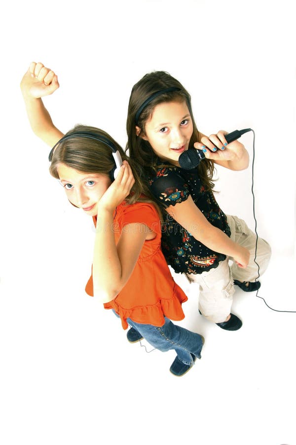 Two young girls singing and listening to music. Two young girls singing and listening to music.