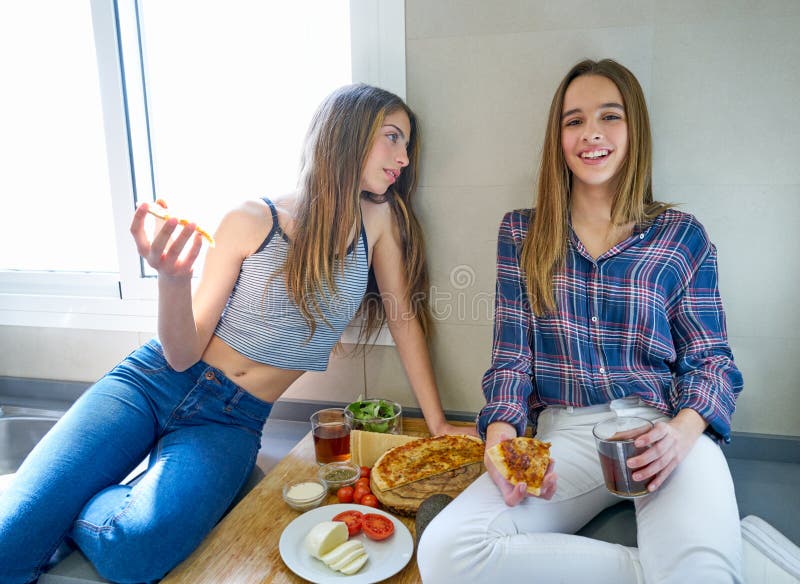Best friend teen girls eating pizza in the kitchen at lunch having fun. Best friend teen girls eating pizza in the kitchen at lunch having fun