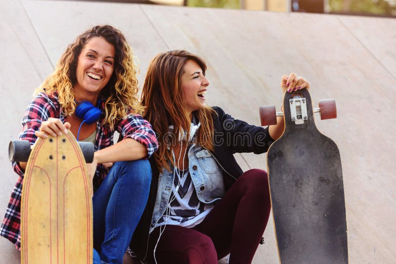 Filles de patin s'asseyant dans la rue traînant image stock Filles de patin s'asseyant dans la rue traînant image stock