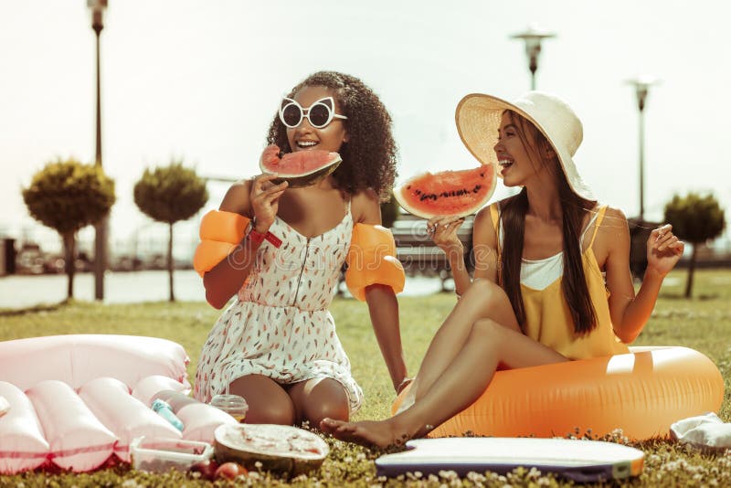 Filles heureuses ayant une conversation et tenant la pastèque dans des mains photos libres de droits Filles heureuses ayant une conversation et tenant la pastèque dans des mains photos libres de droits