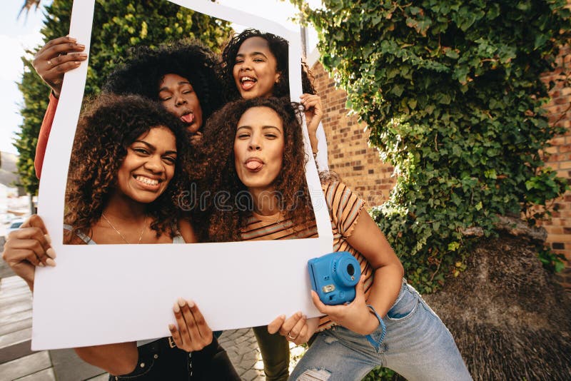 Filles posant avec le cadre de tableau vide photos stock Filles posant avec le cadre de tableau vide photos stock