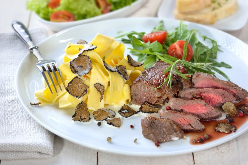 Fried beef tenderloin with Italian pasta and slices of fresh black autumn truffles, served with a mixed side salad and baguette. Fried beef tenderloin with Italian pasta and slices of fresh black autumn truffles, served with a mixed side salad and baguette