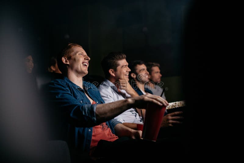 Group of friends sitting in multiplex movie theater. Young people watching movie in cinema hall and smiling. Group of friends sitting in multiplex movie theater. Young people watching movie in cinema hall and smiling.