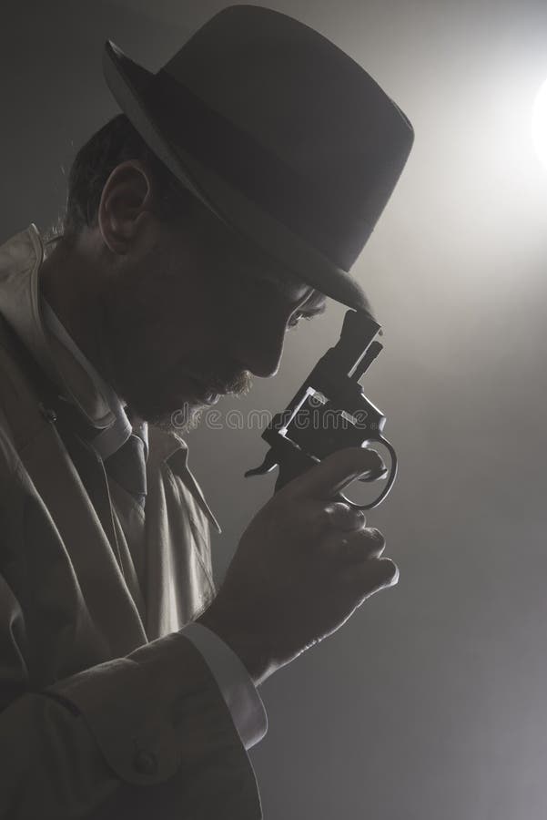 Film noir: agente investigativo nello scuro con una pistola fotografie stock libere da diritti Film noir: agente investigativo nello scuro con una pistola fotografie stock libere da diritti