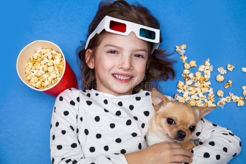 Filme de observação da menina e do cão pequeno nos vidros 3D com pipoca fotos de stock royalty free Filme de observação da menina e do cão pequeno nos vidros 3D com pipoca fotos de stock royalty free