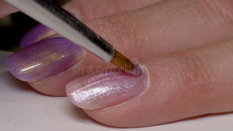 Filme de uma mulher que aplica esmalte de unhas com brilho nas unhas com fundo desfocado video estoque