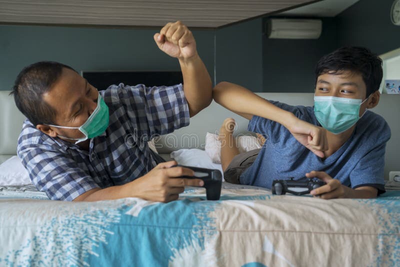 Fils et père de jouer le jeu vidéo avec le masque médical photos libres de droits