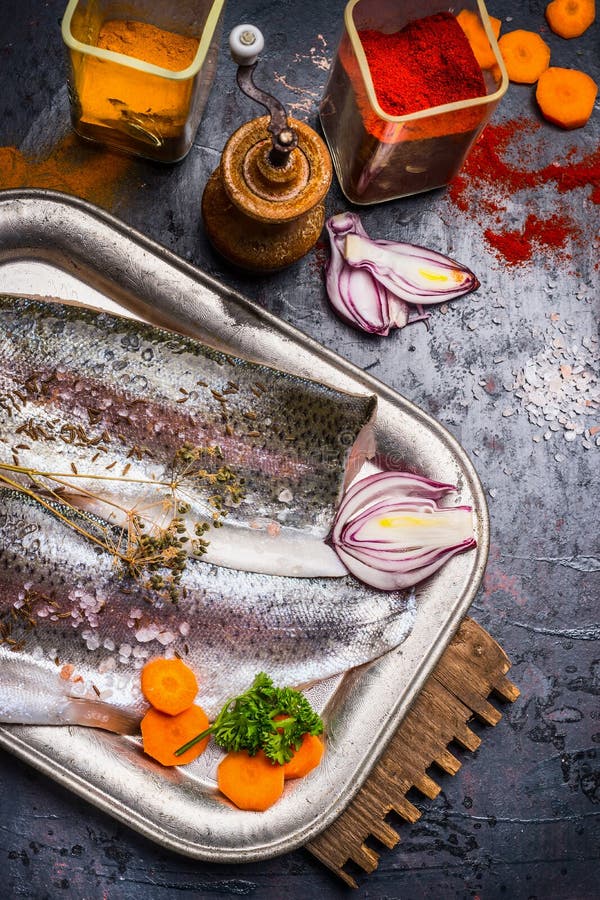 Filéer för rå fisk med kryddor som lagar mat förberedelsen på det mörka köksbordet