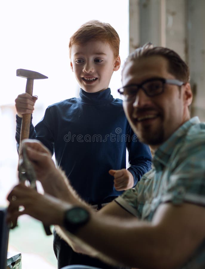 Fim acima o filho pequeno ajuda seu pai a fazer reparos imagem de stock royalty free Fim acima o filho pequeno ajuda seu pai a fazer reparos imagem de stock royalty free