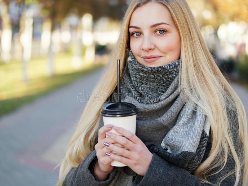 Fin extérieure vers le haut de tir de femme blonde élégante de l'année 20s dans l'écharpe sur le café ou le thé potable de pause photos stock Fin extérieure vers le haut de tir de femme blonde élégante de l'année 20s dans l'écharpe sur le café ou le thé potable de pause photos stock