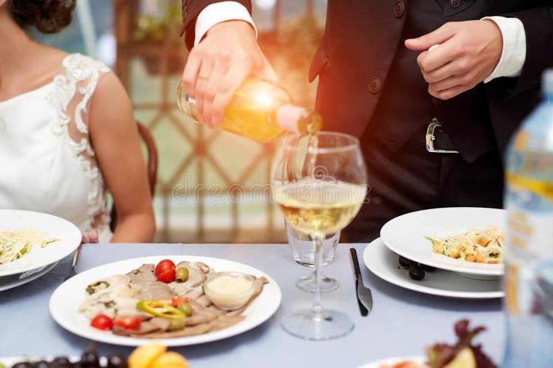 Fin horizontale d'homme caucasien dans le costume noir et la chemise blanche versant le vin rosé dans un verre grand d'une boutei images stock Fin horizontale d'homme caucasien dans le costume noir et la chemise blanche versant le vin rosé dans un verre grand d'une boutei images stock