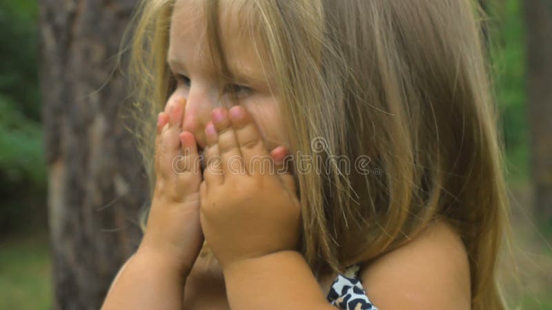 Fin mignonne de petite fille son visage avec des mains