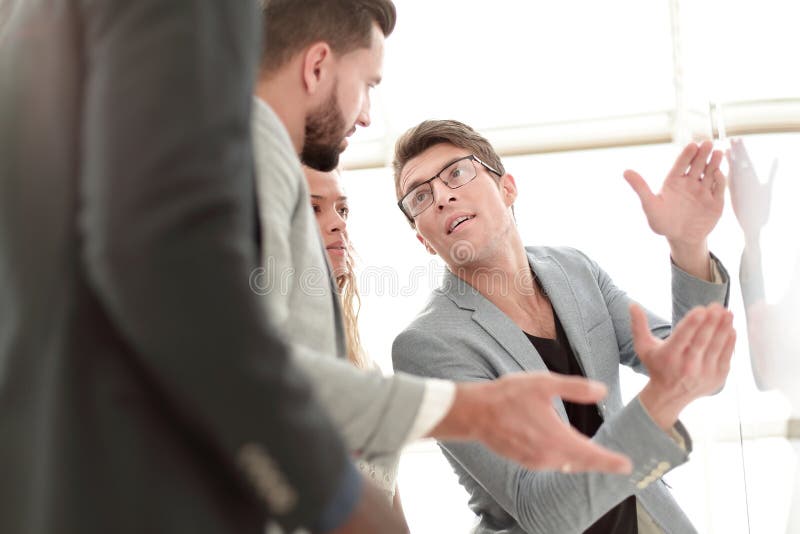 Fin vers le haut parler d'équipe d'affaires, se tenant près du flipchart image stock Fin vers le haut parler d'équipe d'affaires, se tenant près du flipchart image stock