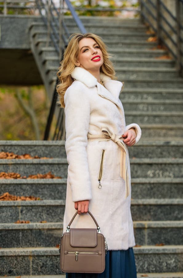 Finally here. girl warm coat stairs background. faux fur coat fashion. stylish business lady leather bag. glamour girl