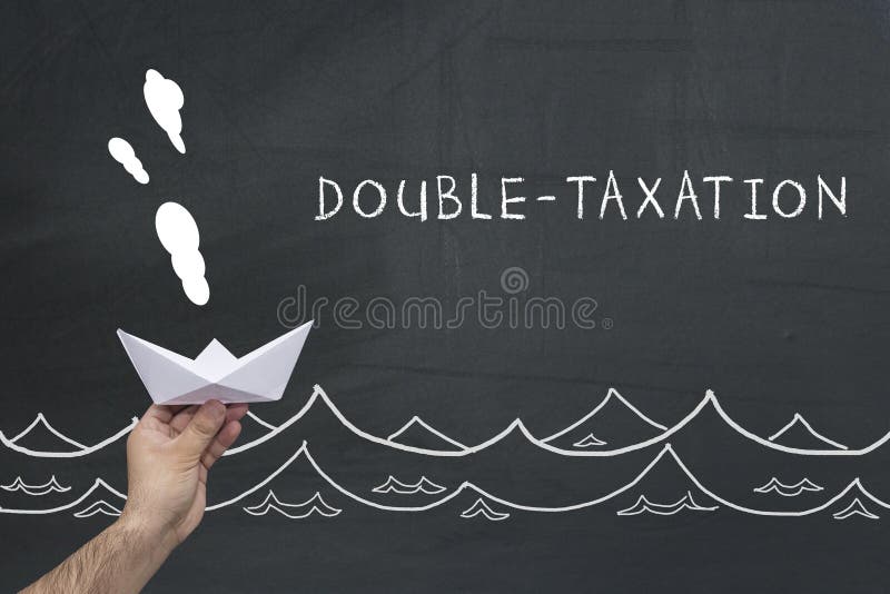 Finance, tax, business concept. hand holding sailing paper ship with text: double taxation royalty free stock image Finance, tax, business concept. hand holding sailing paper ship with text: double taxation royalty free stock image