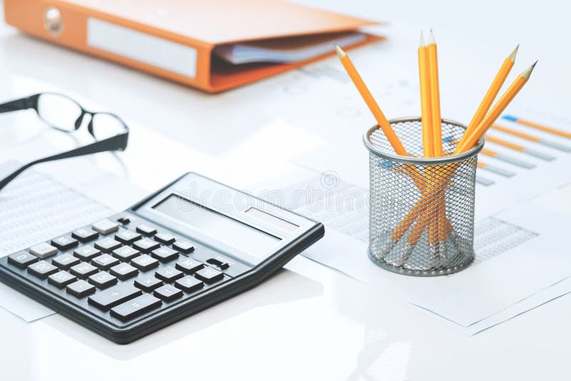 Finance. White Calculator on Financial Graphs on Office Desk Stock