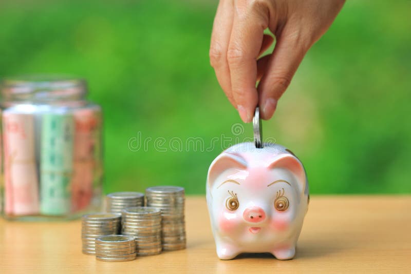 Finance, Woman hand putting a coins money into piggy and banknote in glass bottle with on natural green background, Business