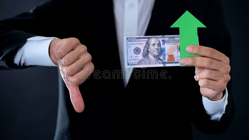 Finansiell konsulent med dollarsedlar som ner visar tummar och den gröna pilen royaltyfri bild Finansiell konsulent med dollarsedlar som ner visar tummar och den gröna pilen royaltyfri bild