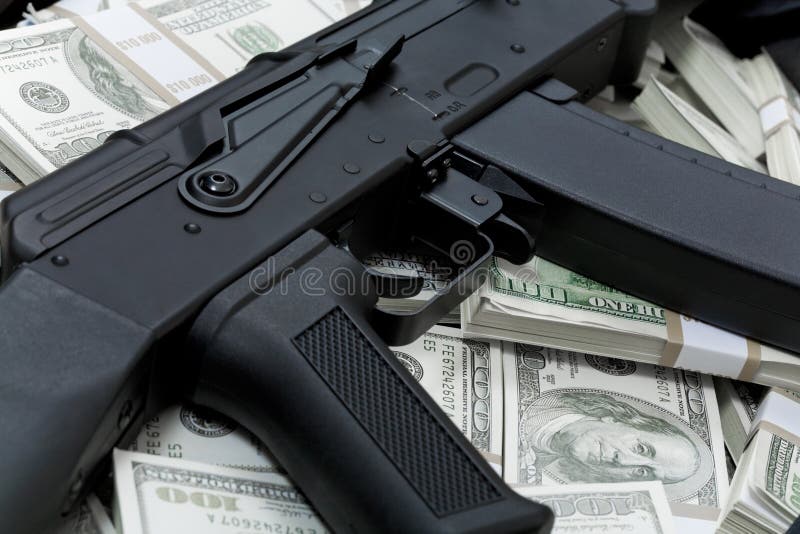 Close-up of black weapon lying on heap of hundred dollar bills. Close-up of black weapon lying on heap of hundred dollar bills