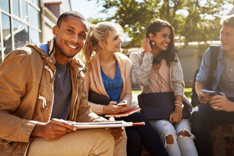 Find yourself a cozy and efficient study group. Portrait of a student studying outside on campus with his classmates. stock photo