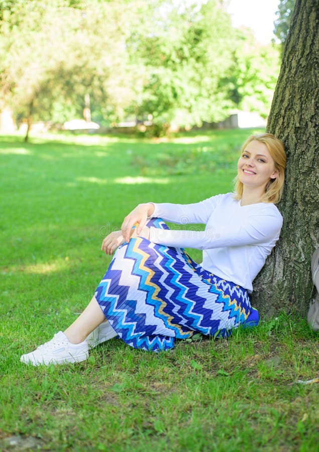 Find peaceful place in park. Give yourself break and enjoy leisure. Girl sit on grass lean on tree trunk relaxing in shadow green nature background. Woman blonde take break relaxing in park. Find peaceful place in park. Give yourself break and enjoy leisure. Girl sit on grass lean on tree trunk relaxing in shadow green nature background. Woman blonde take break relaxing in park.