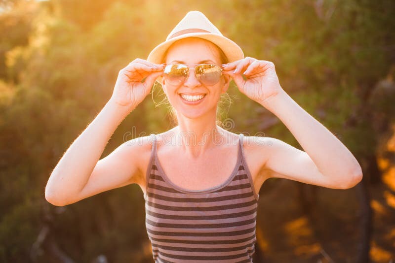 Fine all'aperto sul ritratto di giovani bei occhiali da sole d'uso sorridenti felici della donna, cappello di paglia, posante nel immagini stock Fine all'aperto sul ritratto di giovani bei occhiali da sole d'uso sorridenti felici della donna, cappello di paglia, posante nel immagini stock