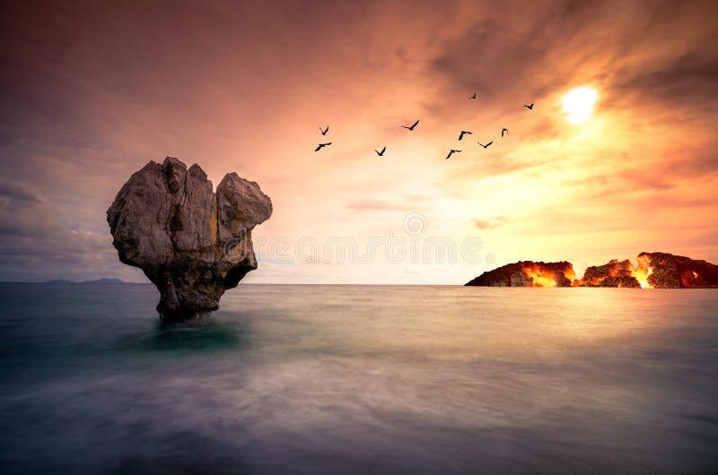 Fine art with lonely rock sculpture in the sea with silhouettes of flying birds and a burning island.