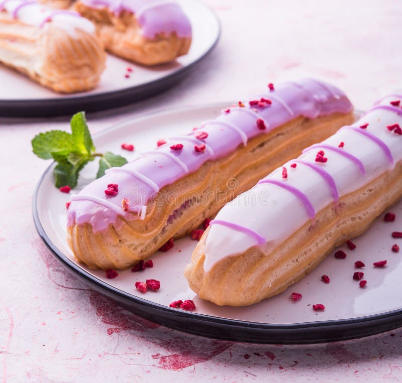 Fine francese violetto-chiaro della prima colazione dei eclairs di mattina rosa del piatto sul dolce crema immagine stock Fine francese violetto-chiaro della prima colazione dei eclairs di mattina rosa del piatto sul dolce crema immagine stock
