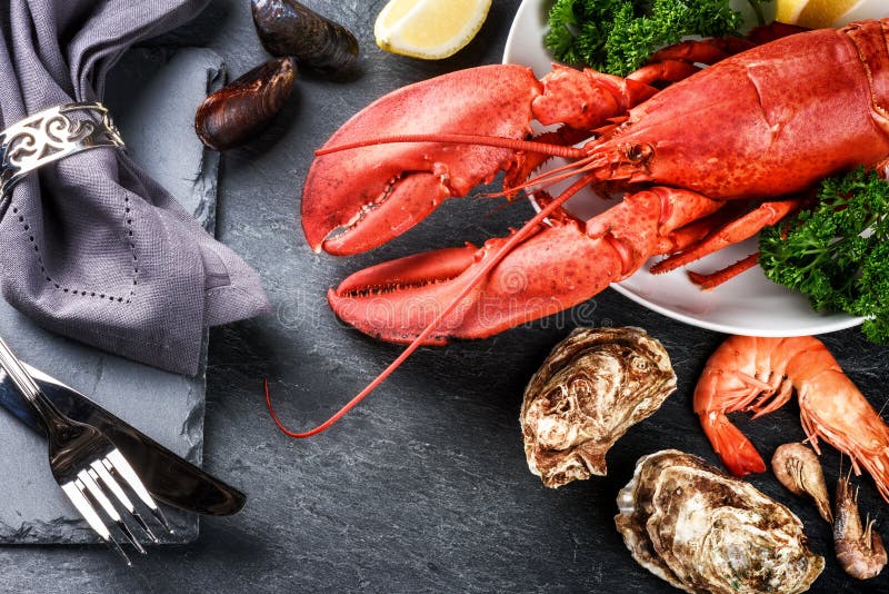 Fine selection of crustacean for dinner. Lobster, oysters and shrimps on dark background