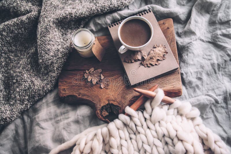 Cup of coffee and candle on rustic wooden serving tray in the cozy bed with blanket. Knitting warm woolen sweater in the autumn weekend, top view. Cup of coffee and candle on rustic wooden serving tray in the cozy bed with blanket. Knitting warm woolen sweater in the autumn weekend, top view.