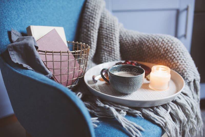 Cozy winter weekend at home. Morning with coffee or cocoa, books, warm knitted blanket and chair. Hygge concept. Cozy winter weekend at home. Morning with coffee or cocoa, books, warm knitted blanket and chair. Hygge concept.