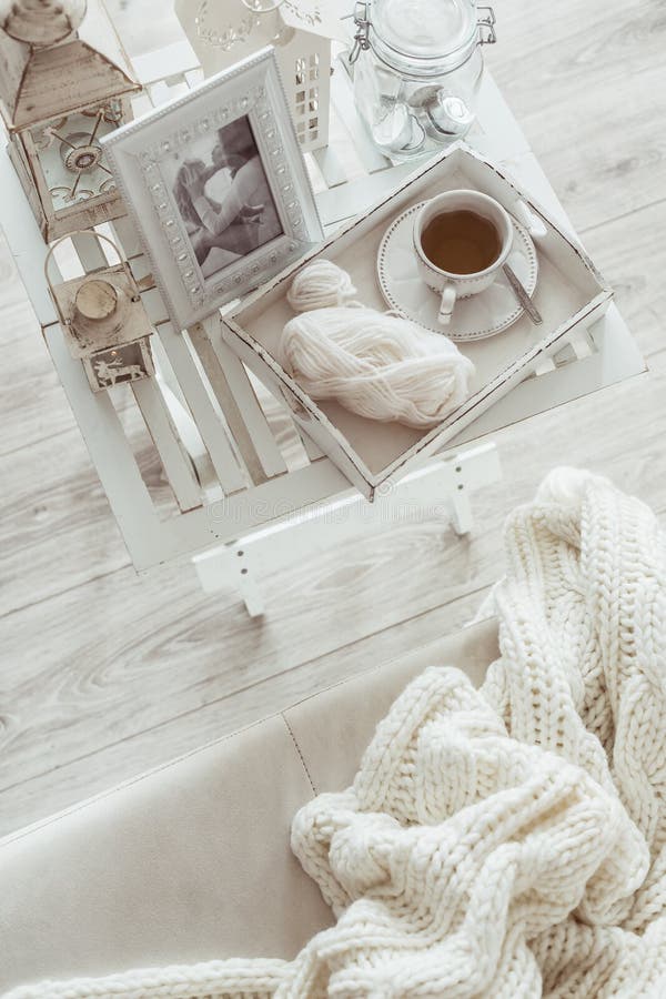 Still life details, cup of tea and knitting on retro vintage wooden tray on a coffee table in living room, top view point. Lazy winter weekend on the sofa. Still life details, cup of tea and knitting on retro vintage wooden tray on a coffee table in living room, top view point. Lazy winter weekend on the sofa.