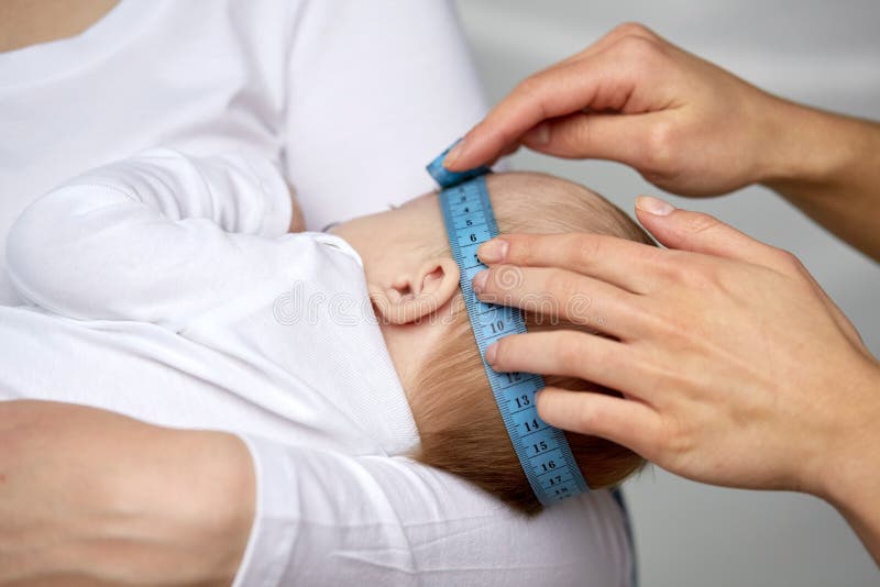 Fine su delle mani con la testa di misurazione del bambino del nastro fotografie stock Fine su delle mani con la testa di misurazione del bambino del nastro fotografie stock